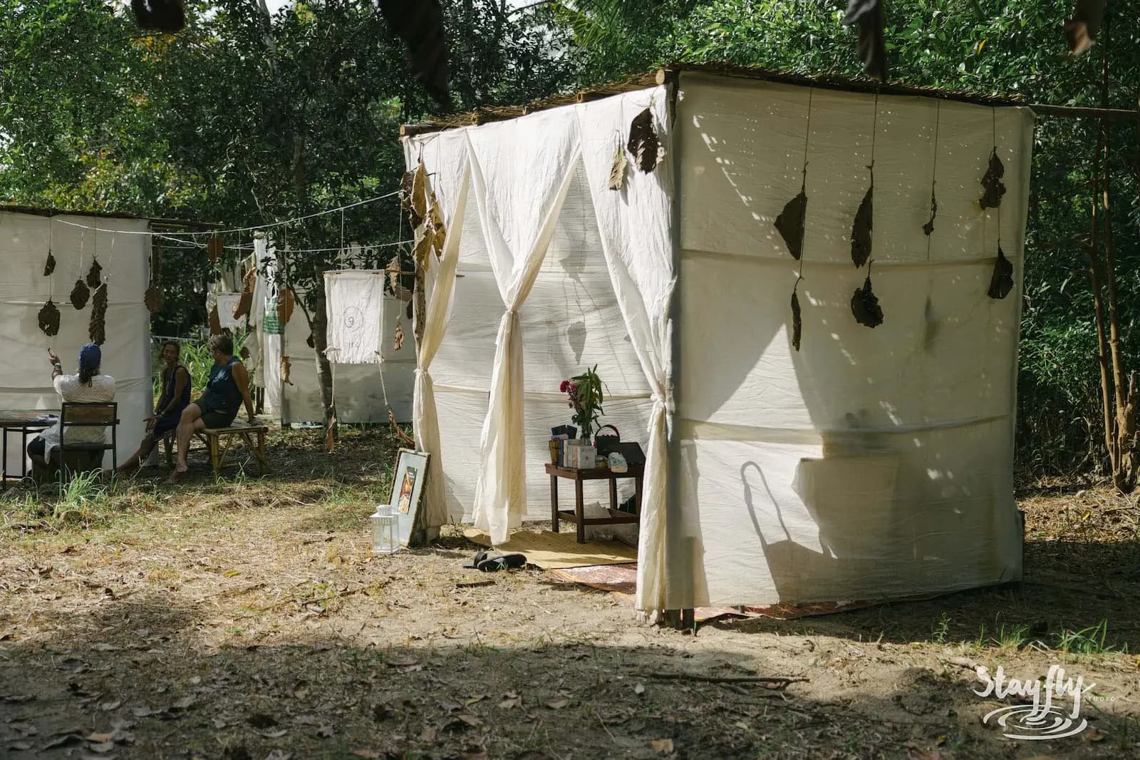 White fabric healing hut with hanging leaf decor.