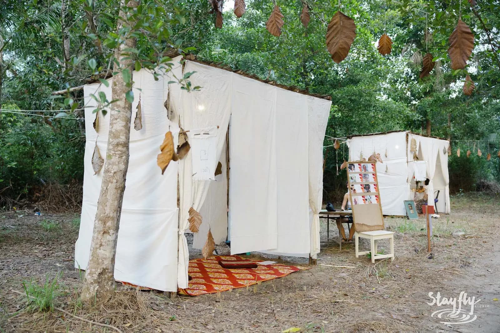 Two white fabric huts with patterned rug at dusk.