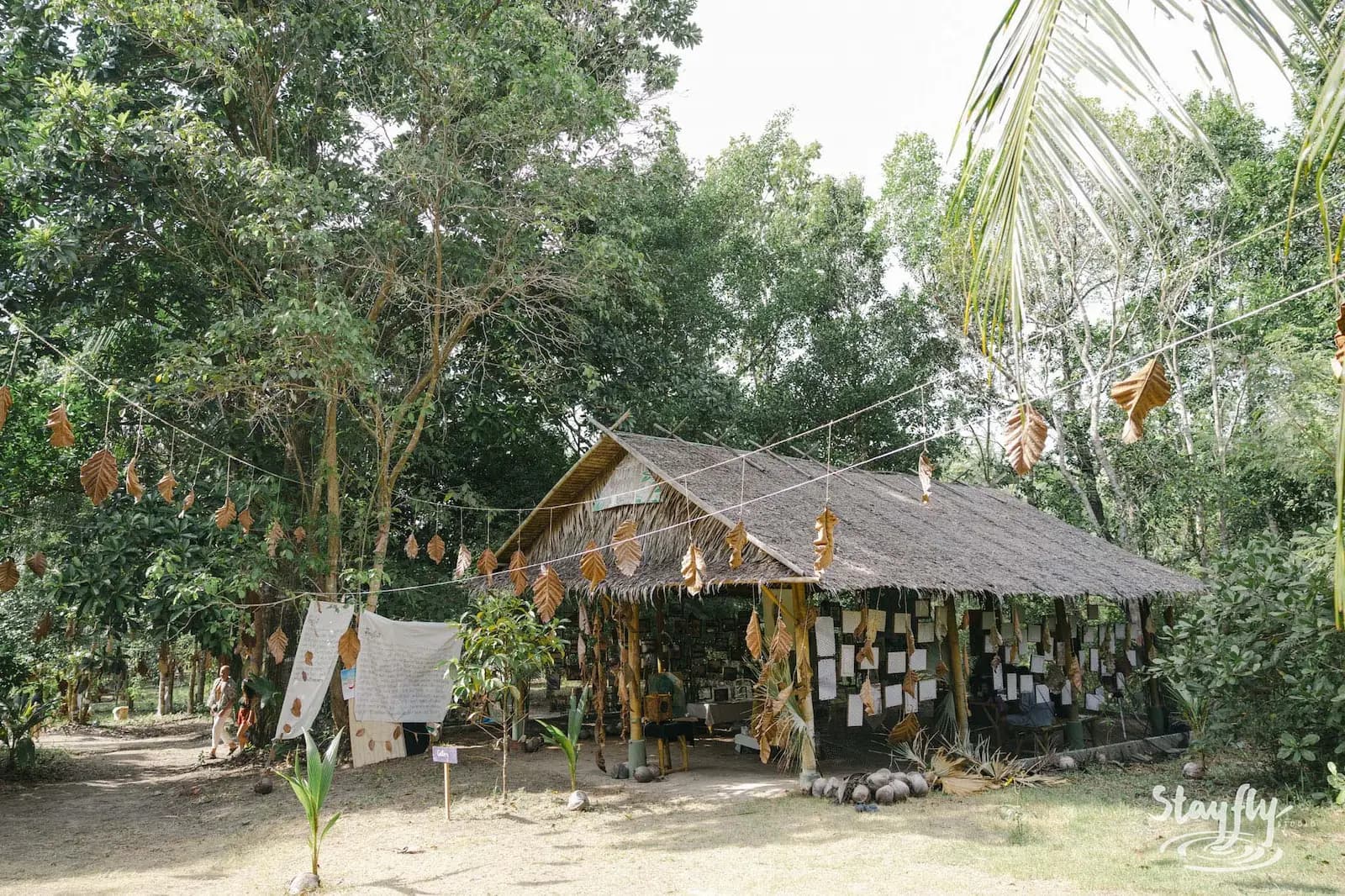 Thatched structure with hanging leaf decorations.