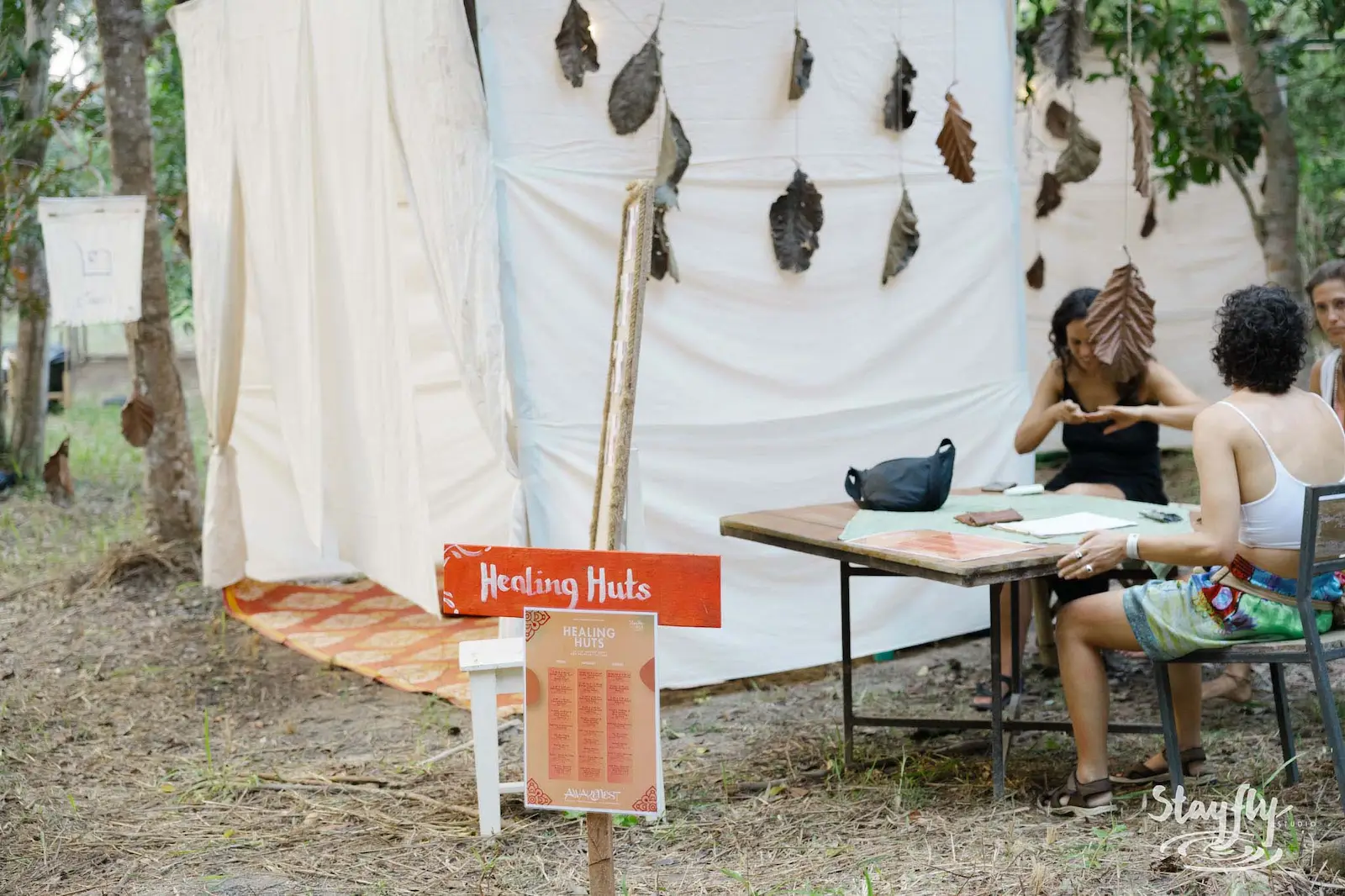 Healing Huts sign with people seated at table.