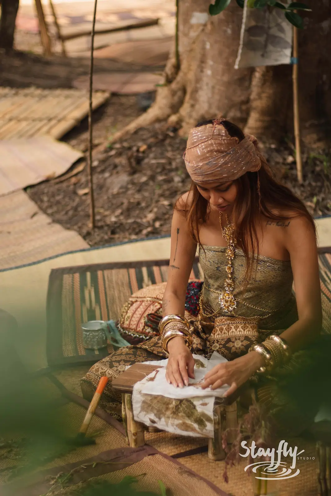 Woman in headscarf preparing herbal compress bundle.