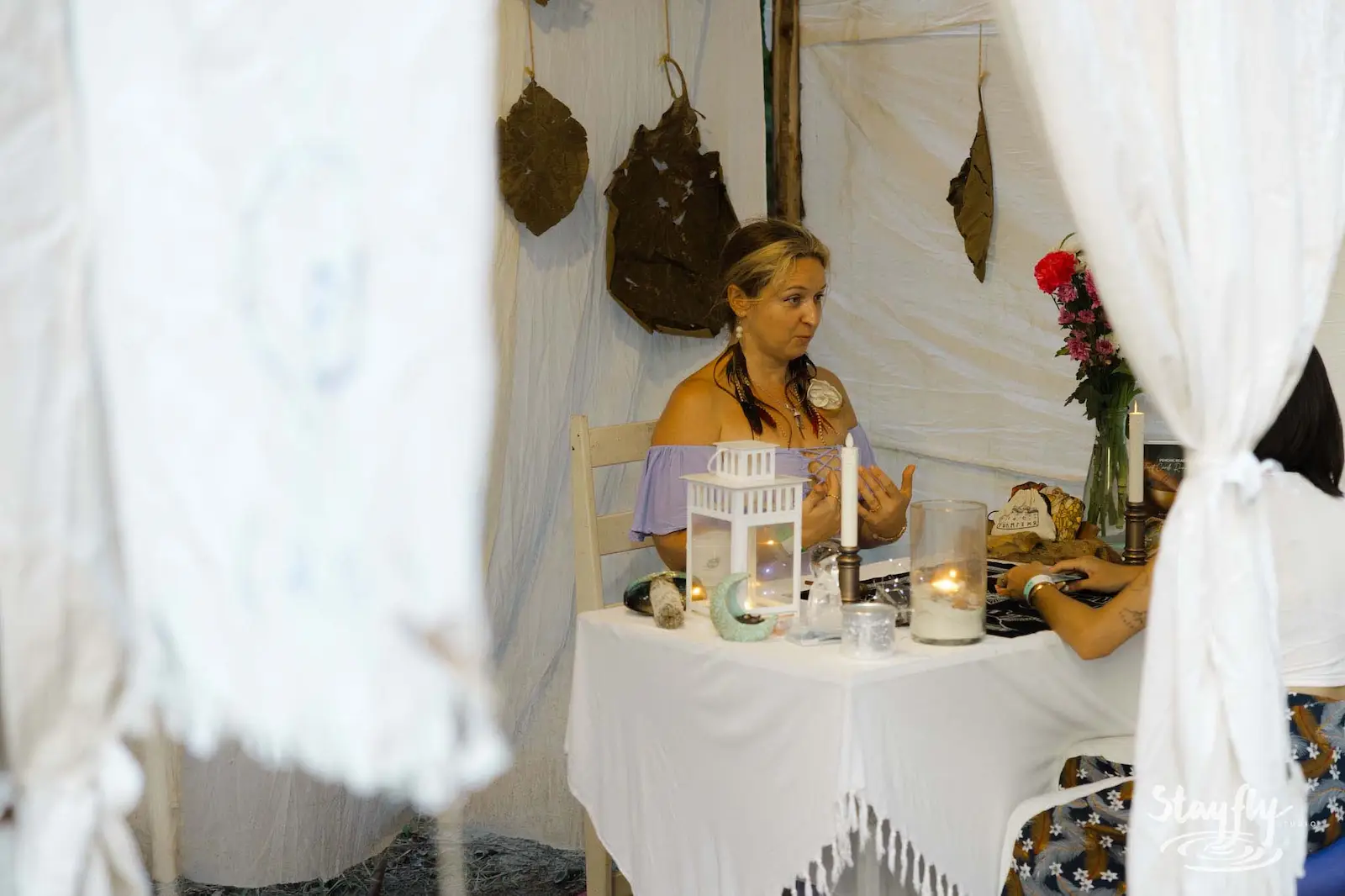 Woman doing tarot reading inside white fabric tent.