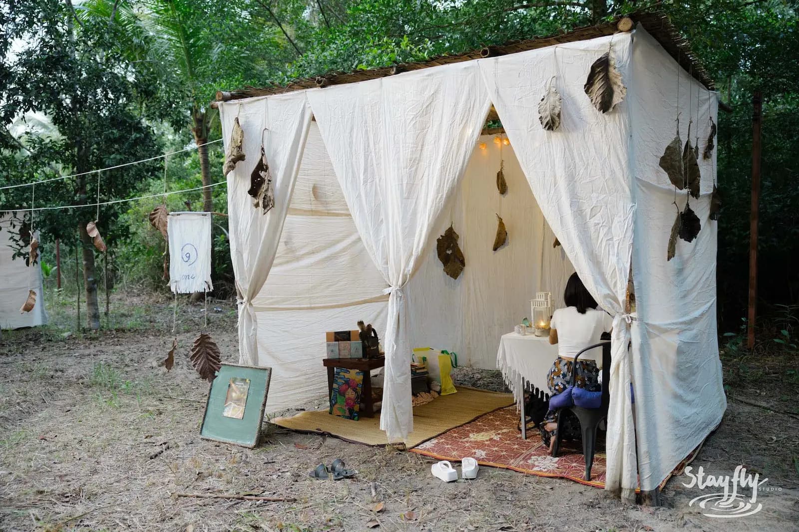 White fabric healing hut with cushions and framed photo.
