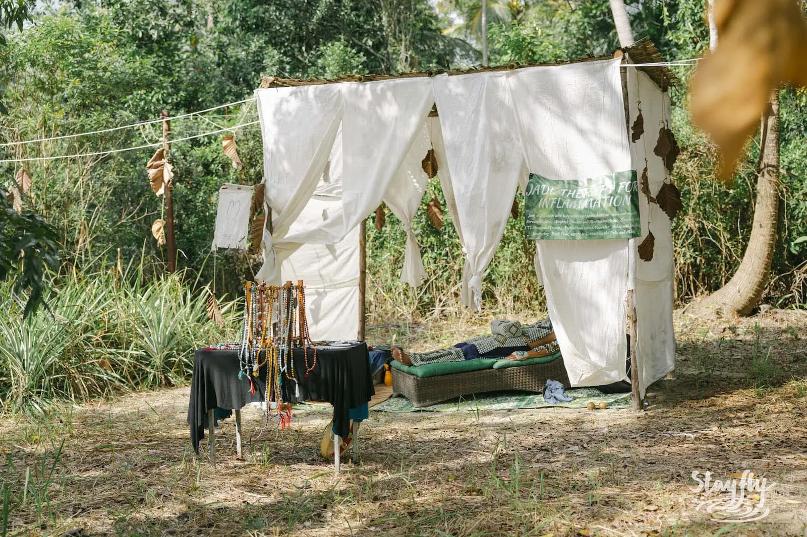 Empty white fabric tent with necklaces hanging outside.