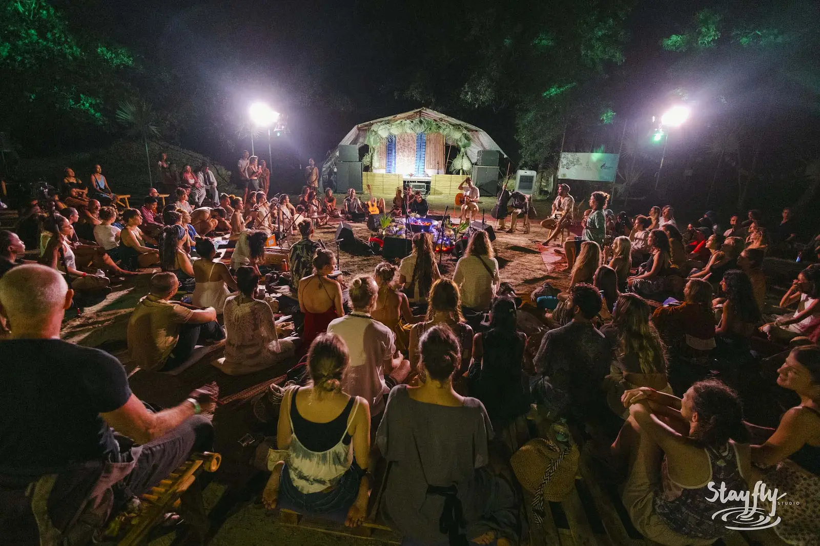 Crowd gathers before lit dome-tent stage at night.