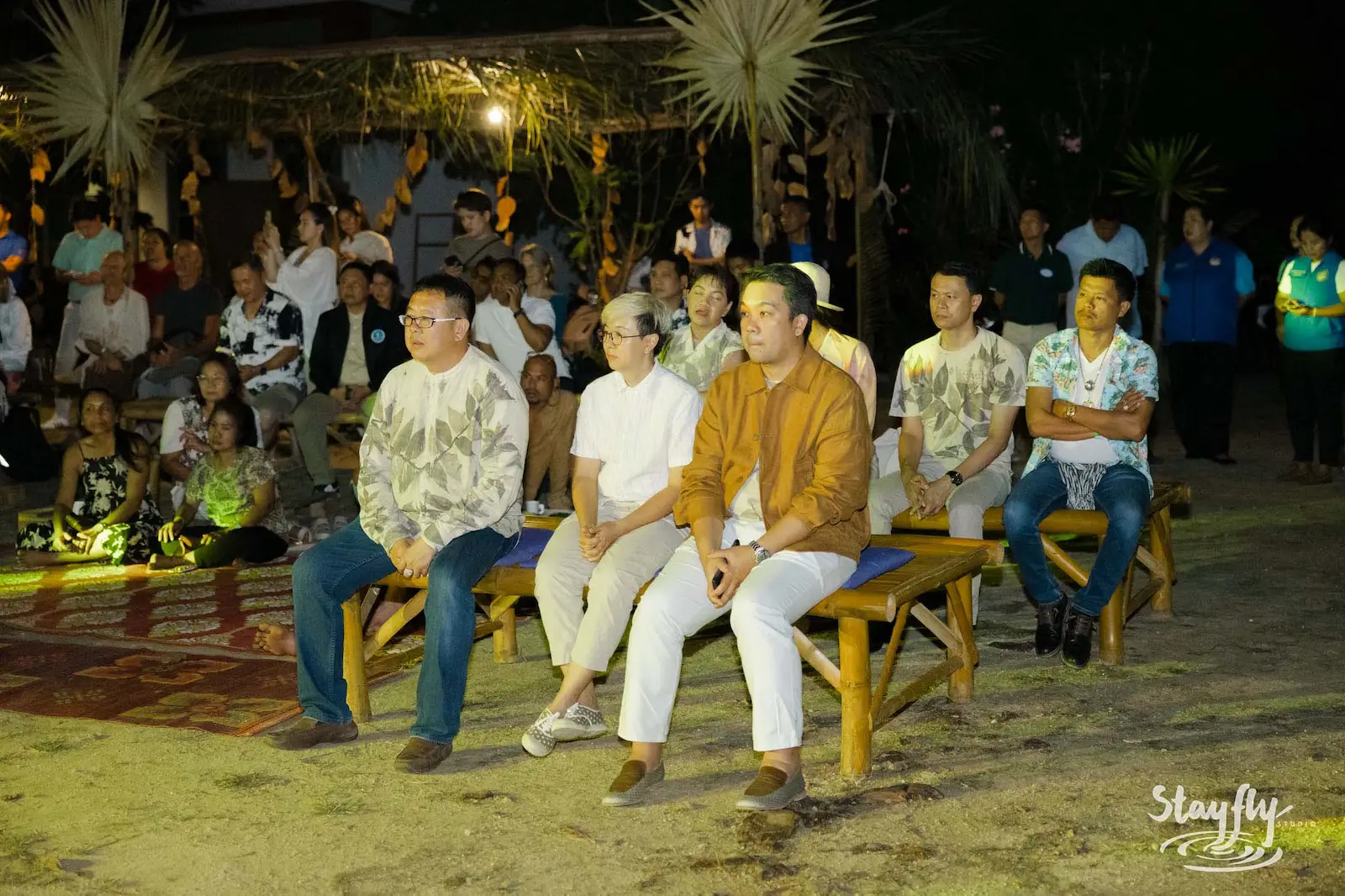 Men in matching shirts seated at night event.