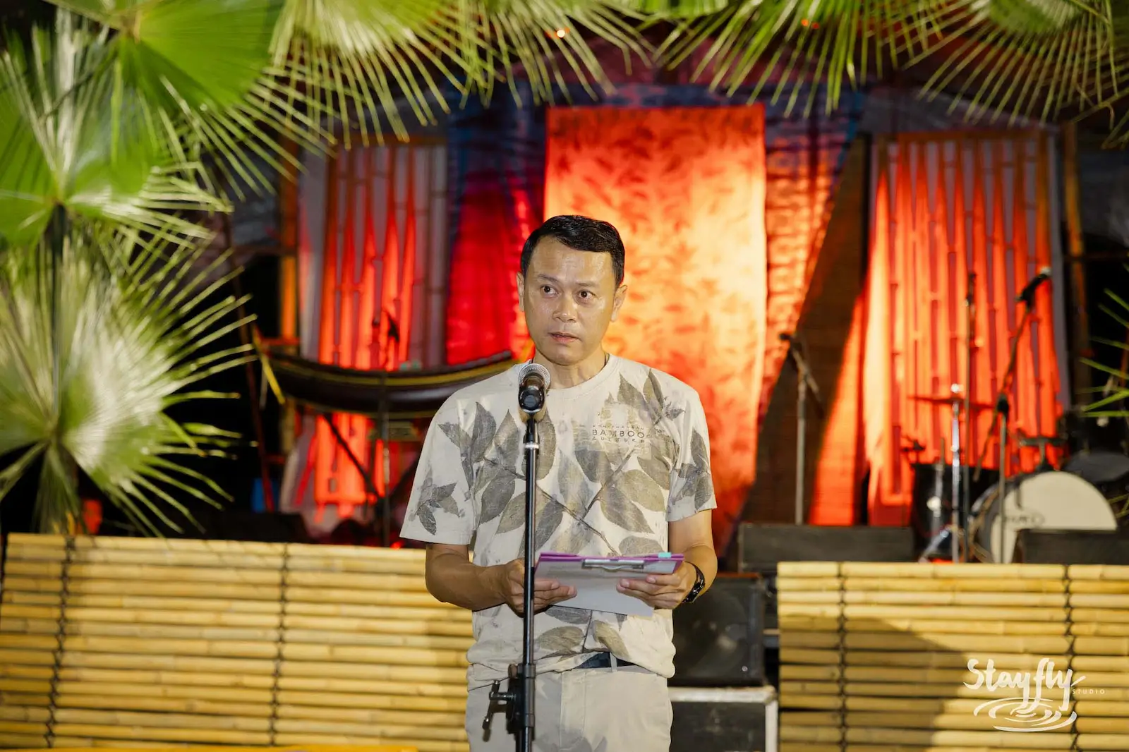 Man speaking at microphone on decorated stage.
