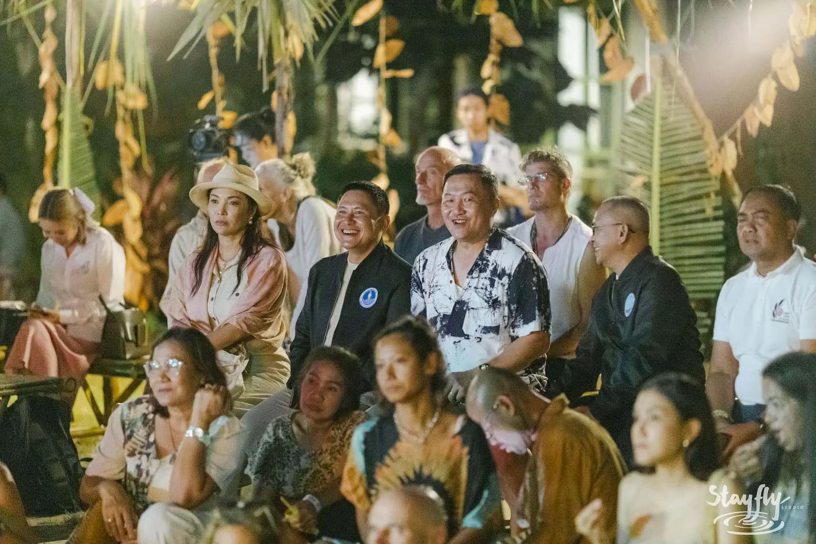 Close group of smiling attendees at night event.