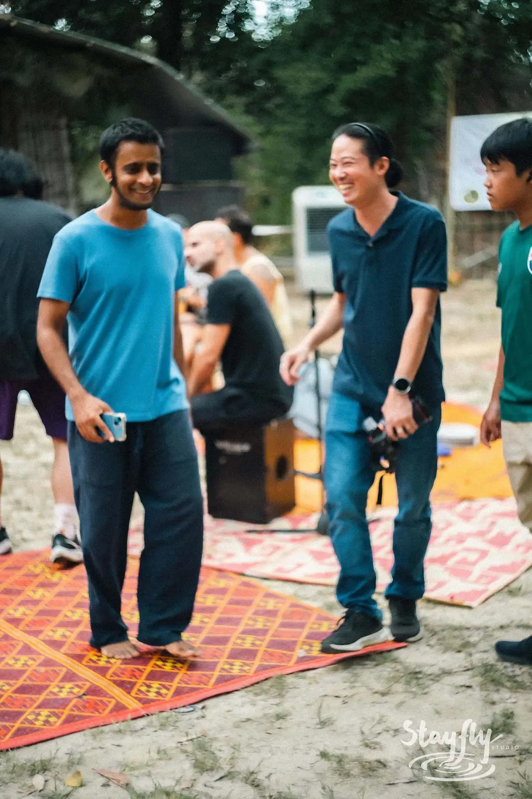 Three men standing together on patterned mats.