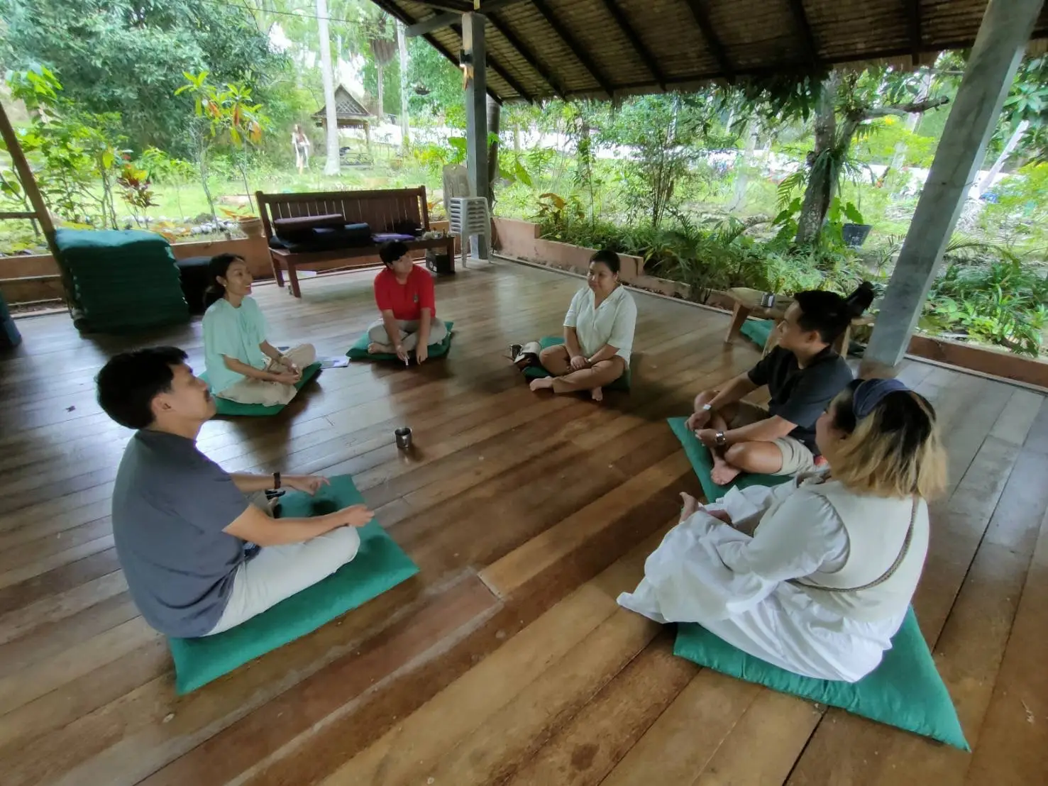 Small group workshop seated in circle outdoors.