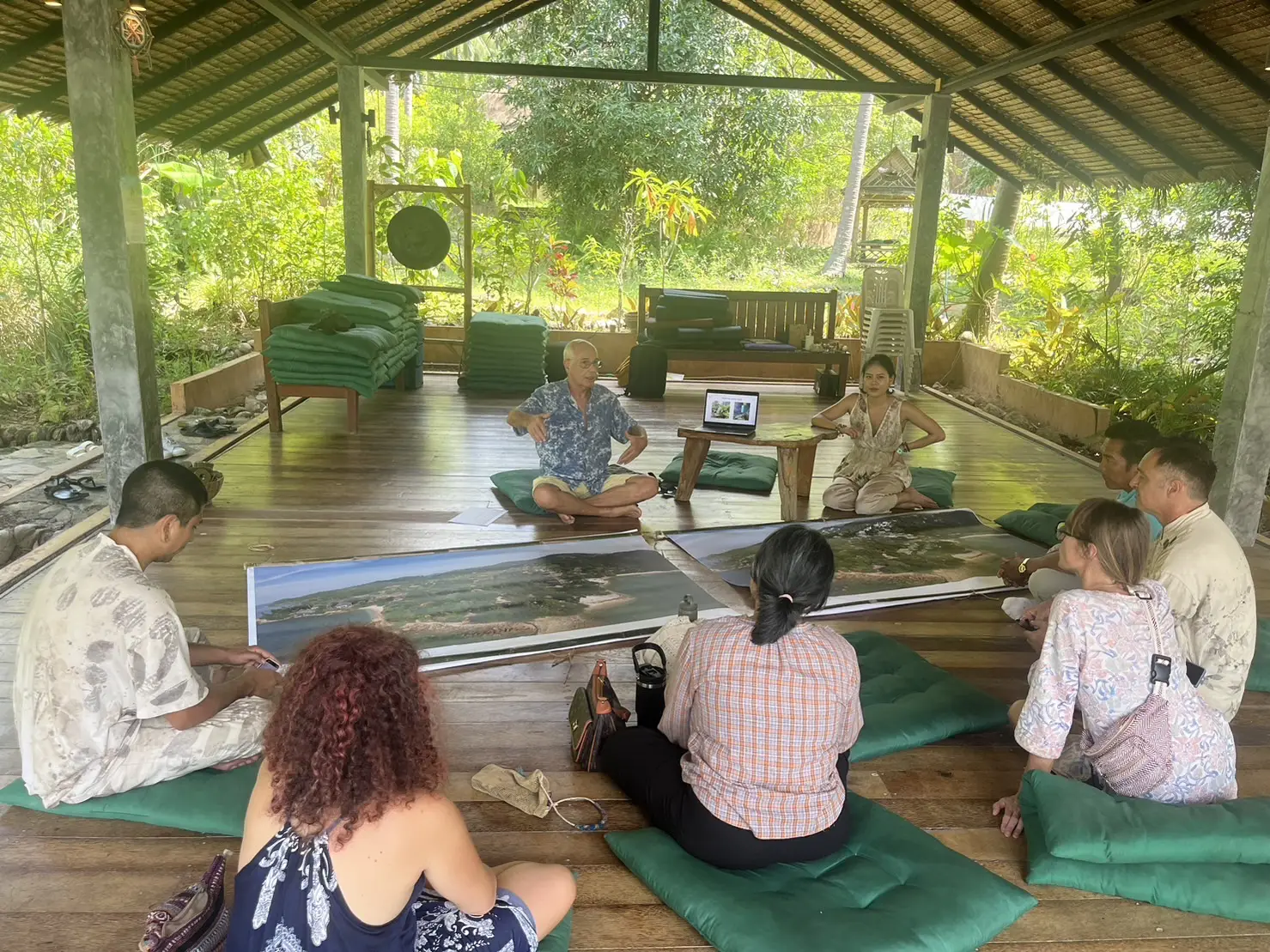 Group examining long scroll on wooden deck floor.