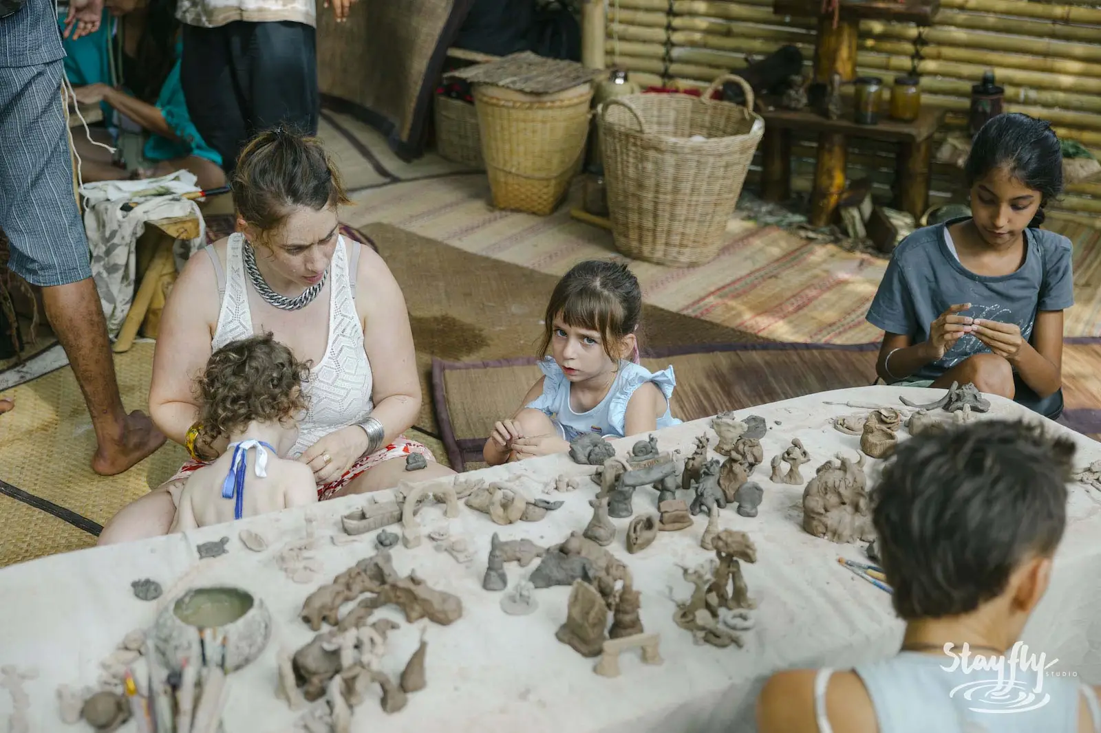 Children and adults shaping clay figures at table.