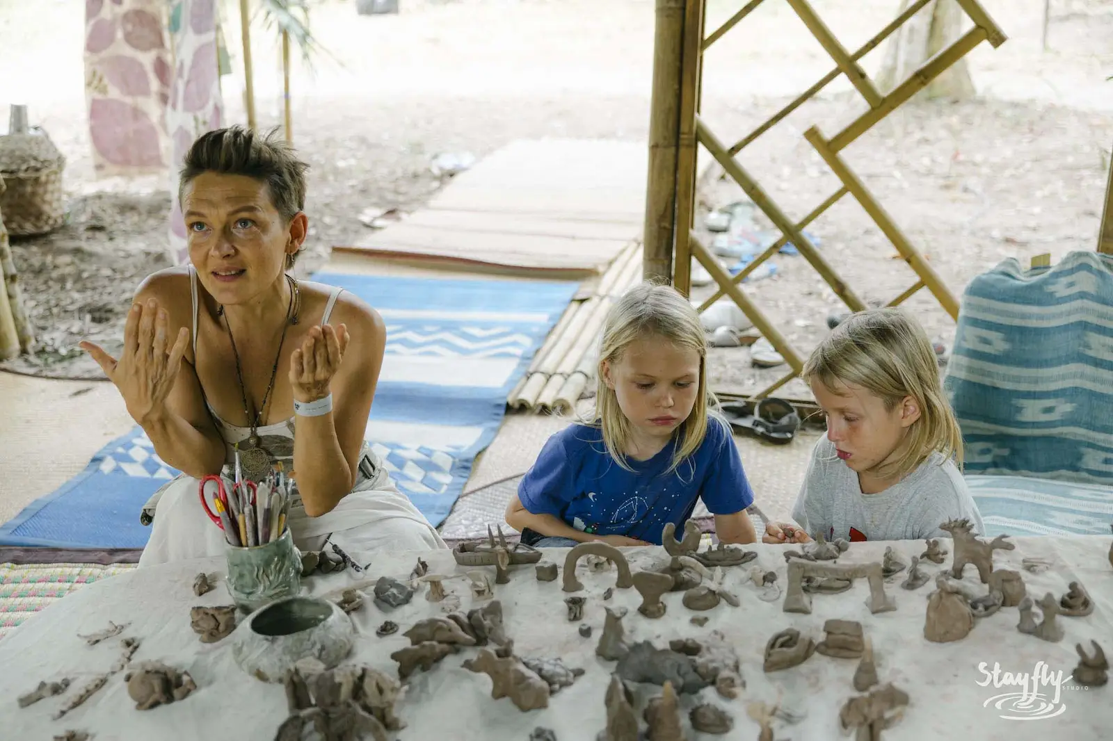 Woman guiding two children making clay figures.