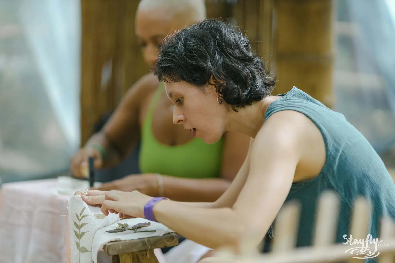 Two women focused on craft table, closer angle.