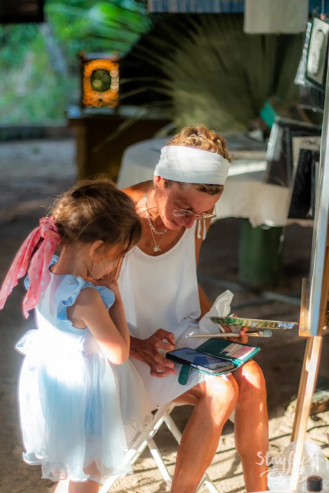 Woman guiding a girl through painting.