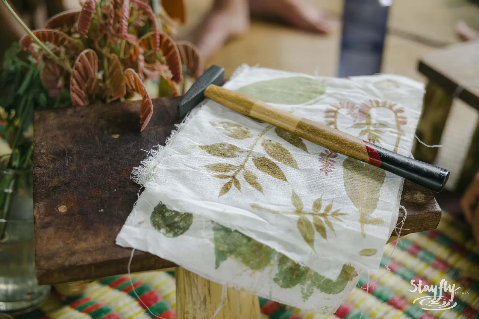 Eco-printed leaf fabric on wooden board with mallet.