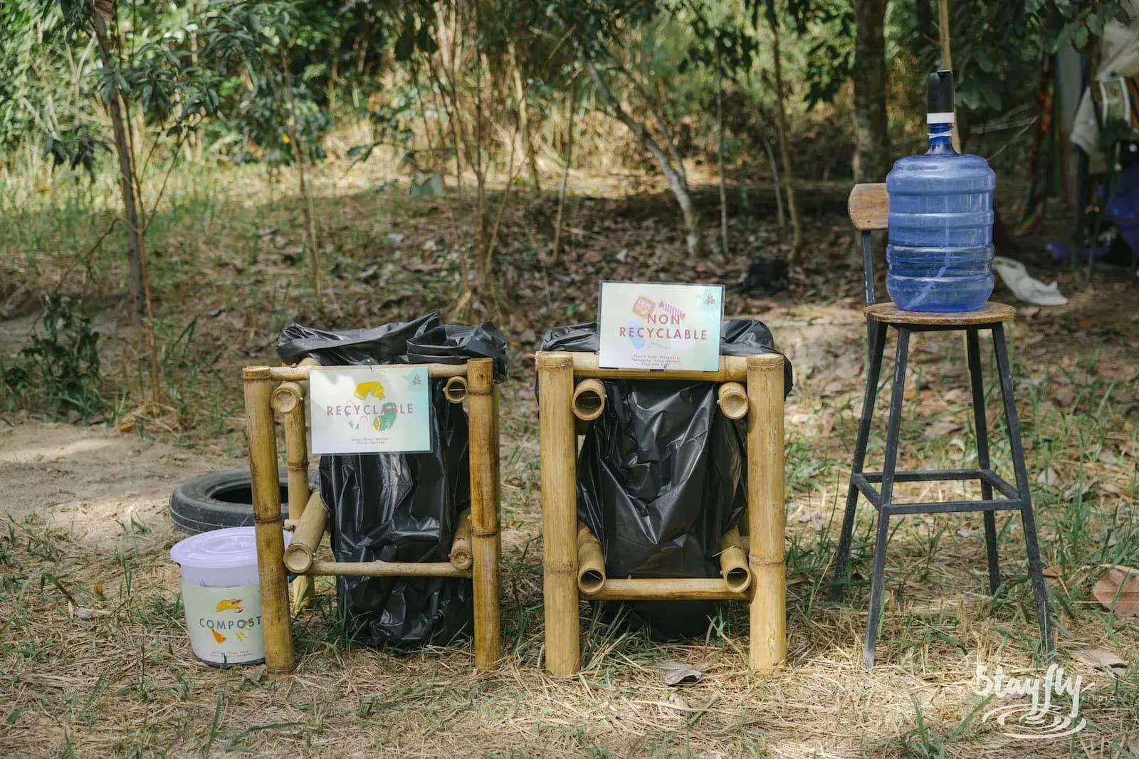 Bamboo-framed waste bins labelled recyclable and non-recyclable, a compost bucket and a water dispenser.