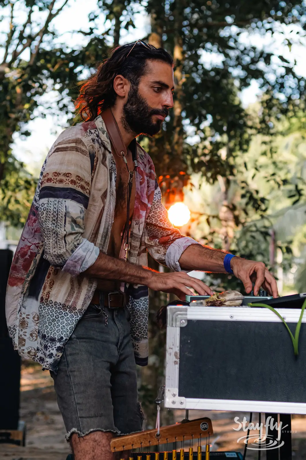 Man adjusts audio equipment case at sunset.