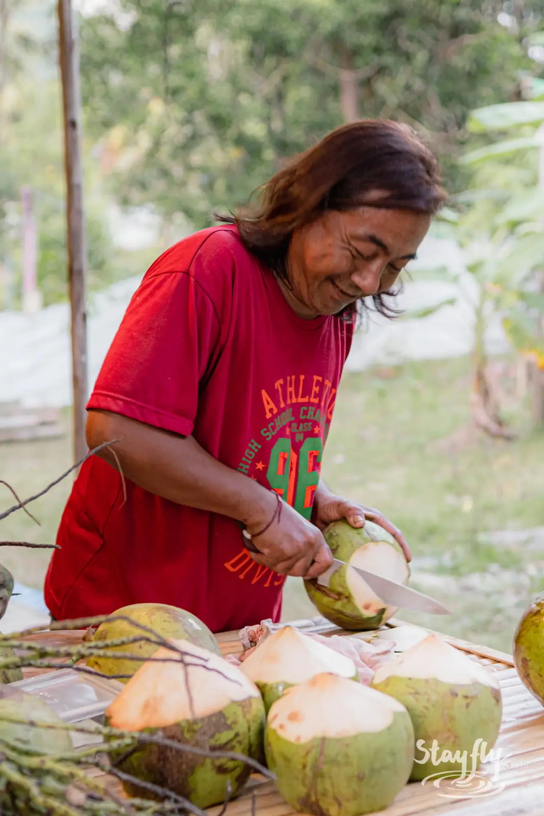 Woman cutting fresh coconuts at a market stall.