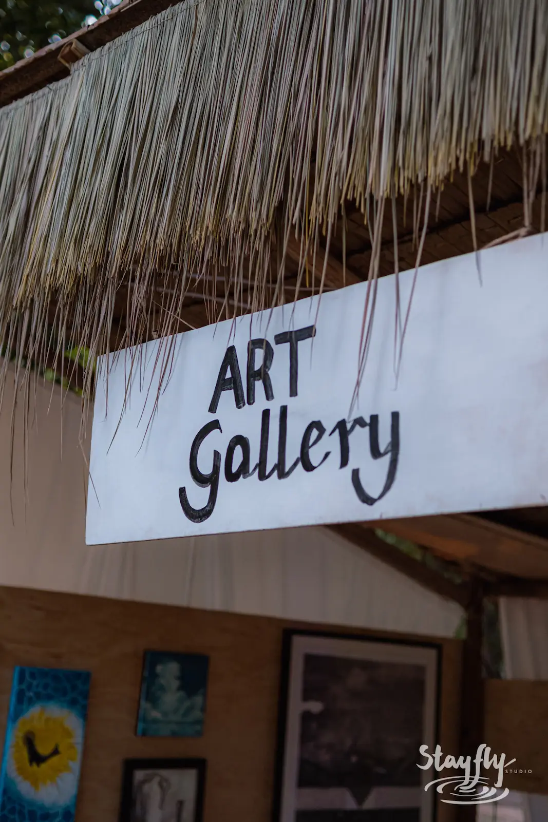 Hand-painted Art Gallery sign under thatched roof.
