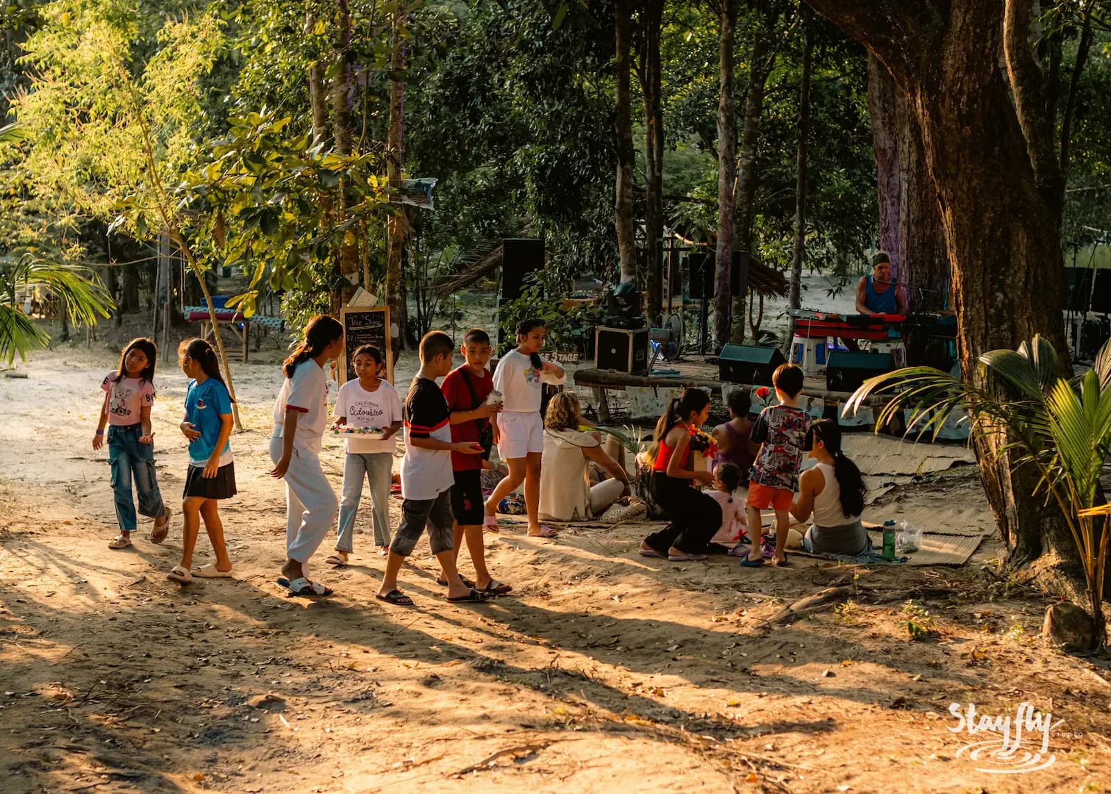 Group walks sandy path among trees.
