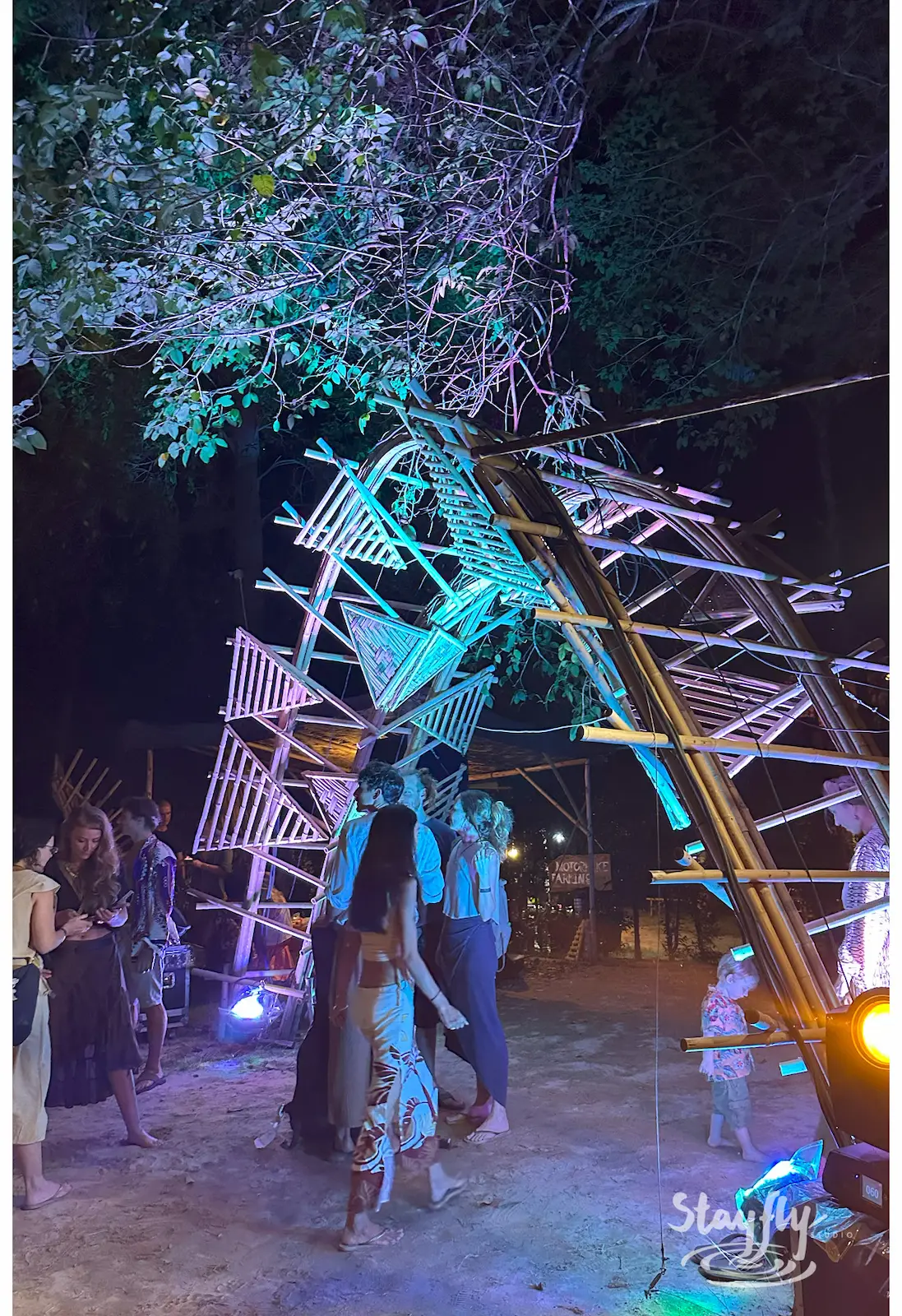 Ladder art installation lit blue in tree at night.
