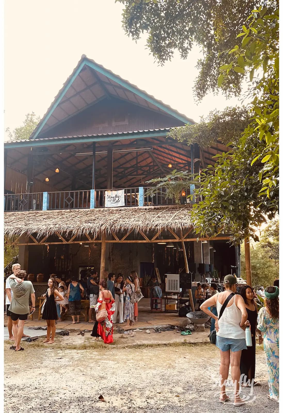 Visitors gathering outside thatched-roof venue at dusk.