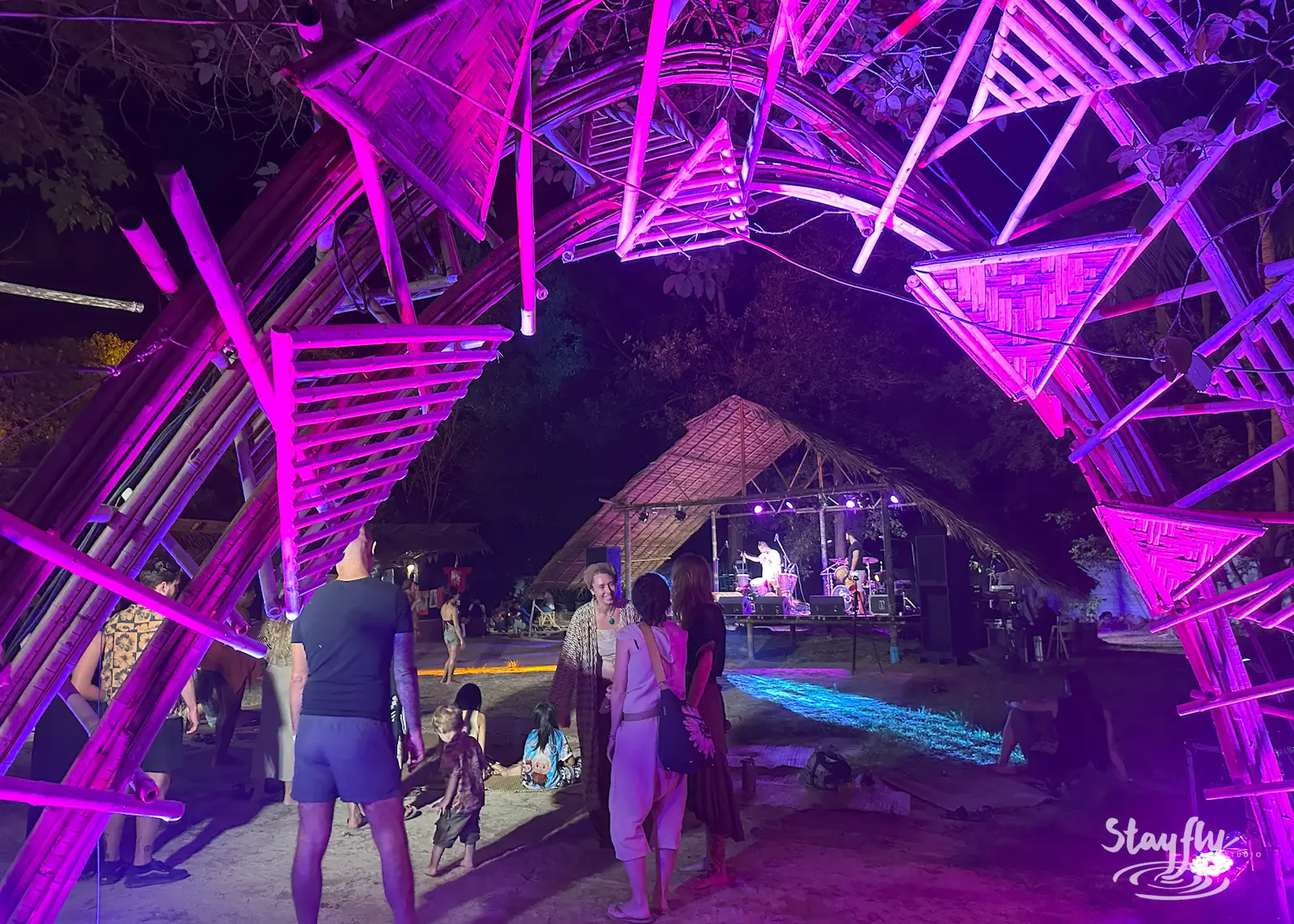 Pink-lit bamboo arch with people passing through.