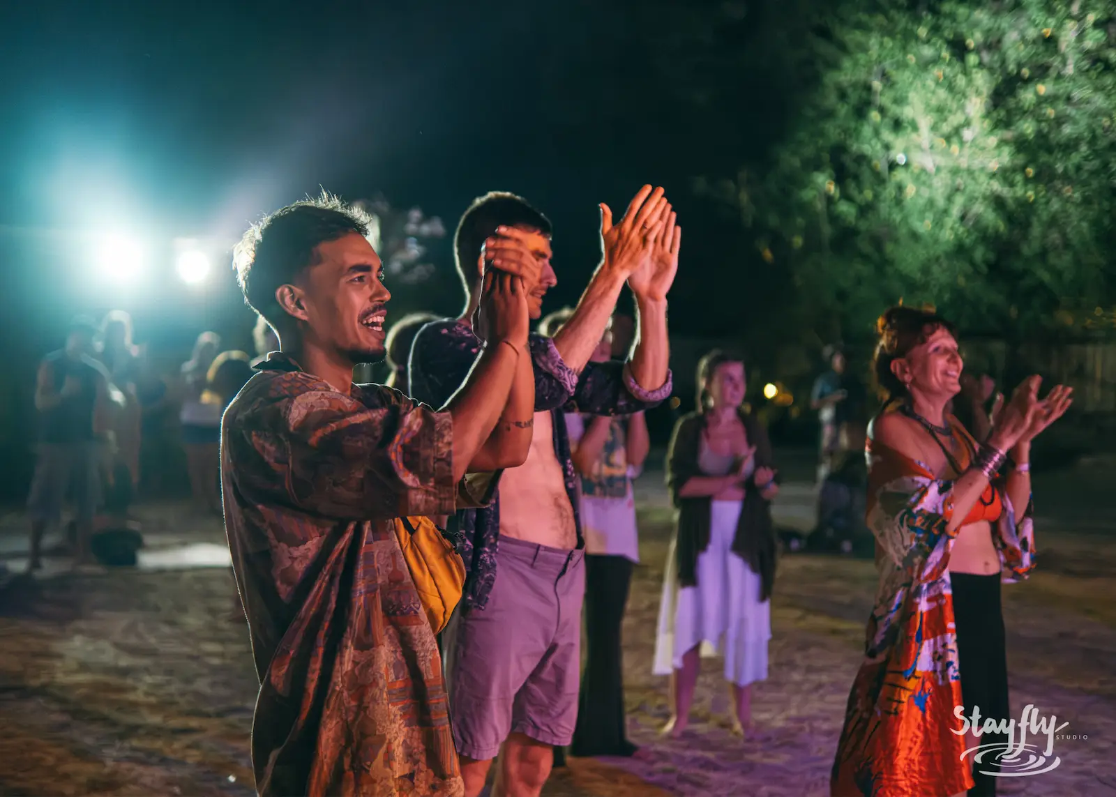 Crowd claps and dances at night.