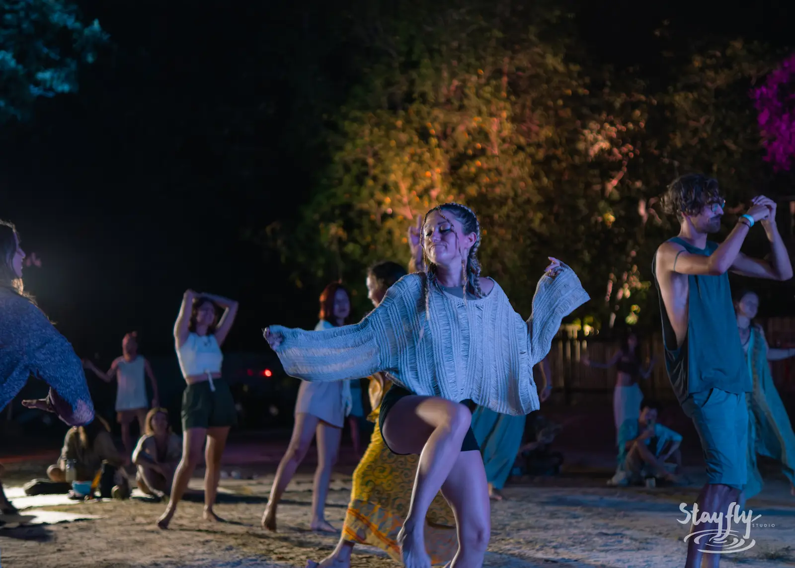 Dancers moving freely at night gathering.