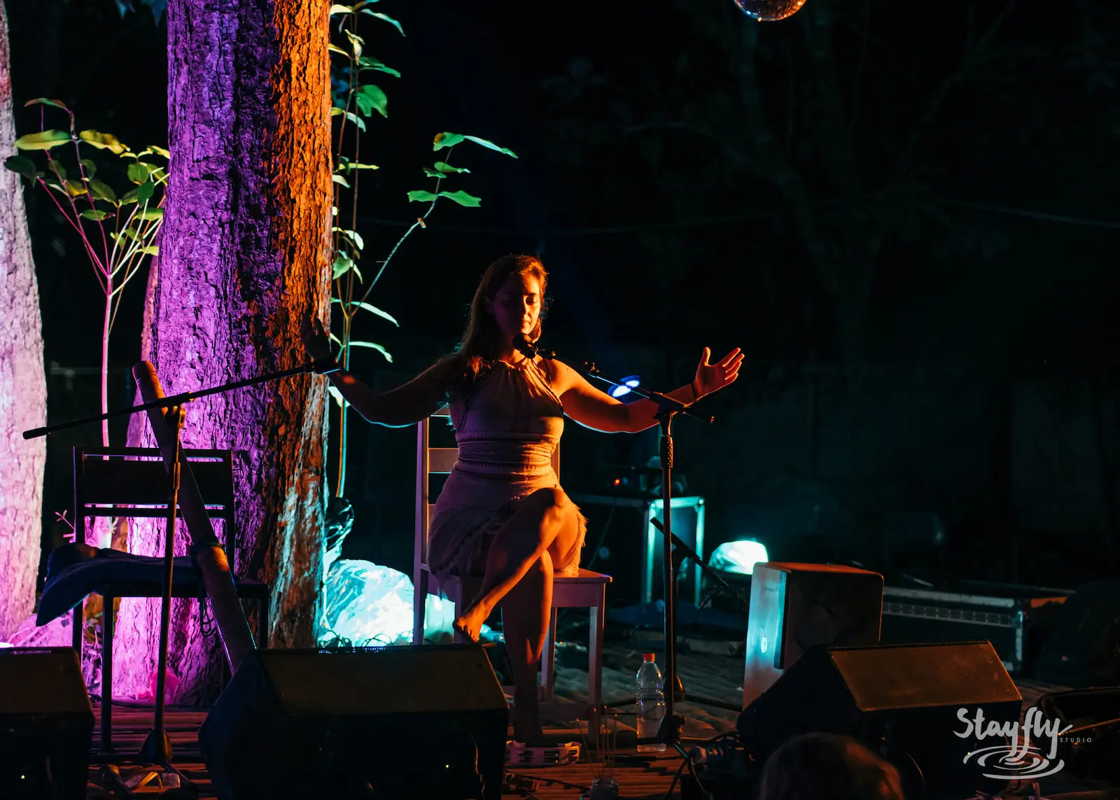 Woman dancing solo near stage at night.