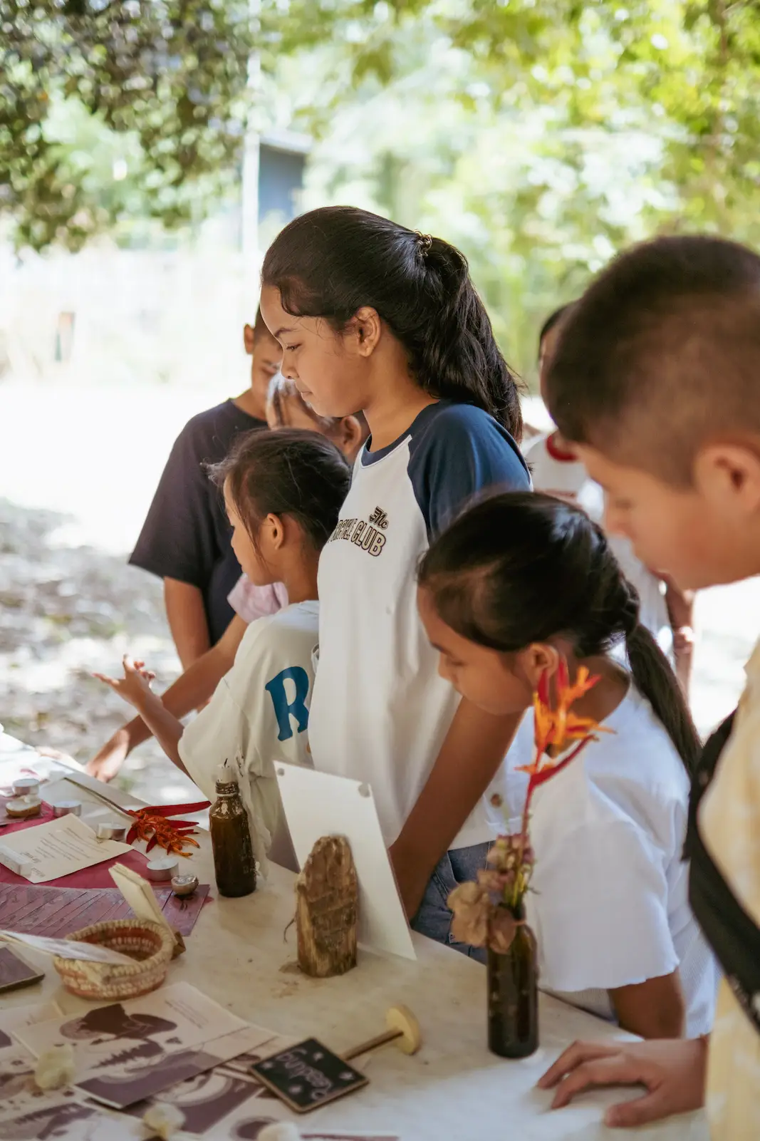 Children and helper arrange dried flowers at table.