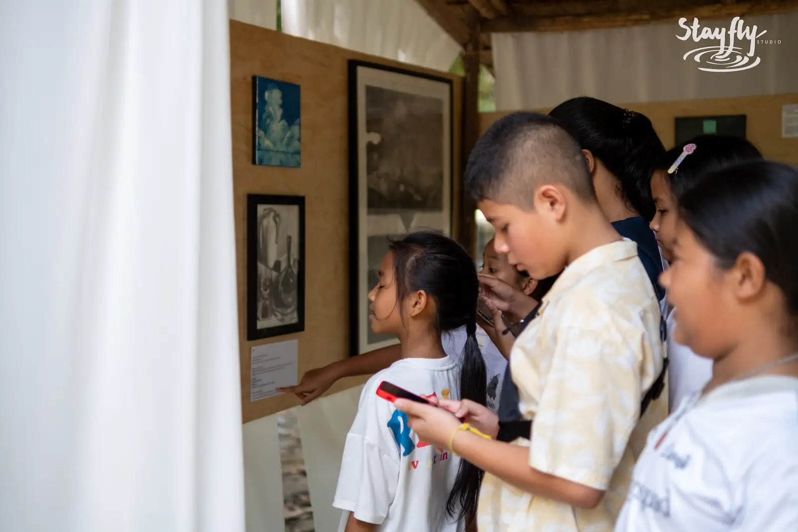 Kids viewing framed artwork on gallery wall.