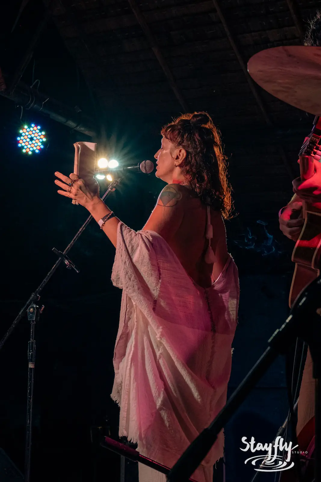 Singer in pink shawl performs at mic.