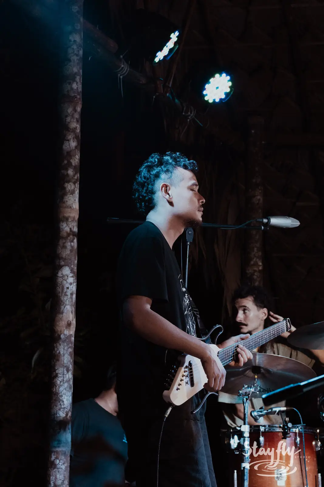Guitarist performs under dim stage lighting.