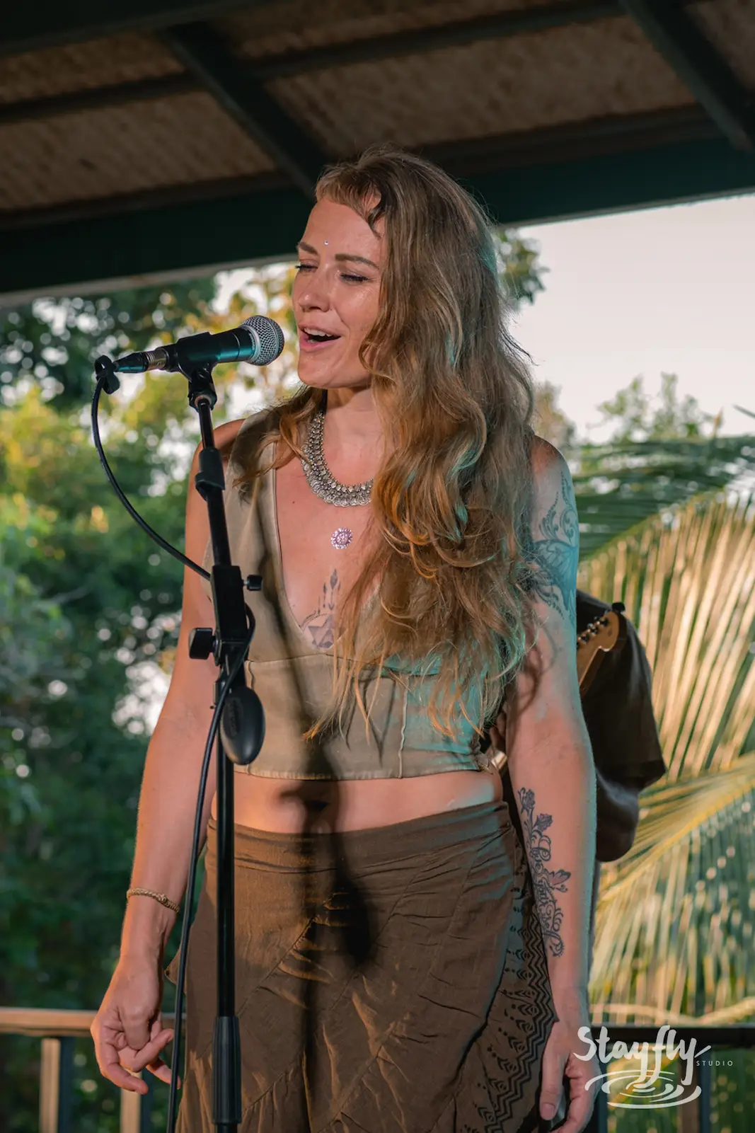 Woman sings on outdoor stage at dusk.