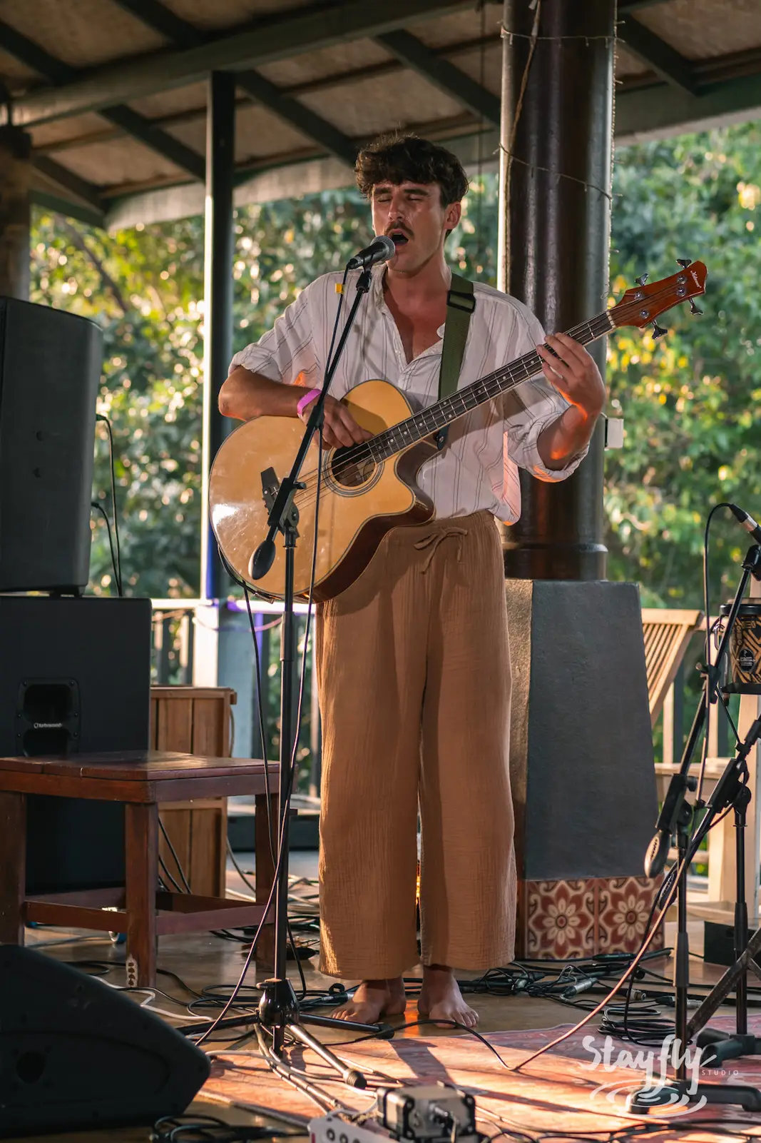 Man plays acoustic guitar on daytime stage.