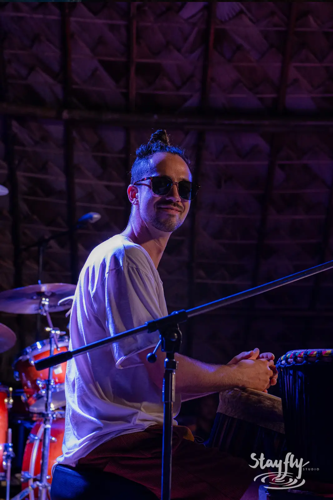 Smiling drummer wearing sunglasses on stage.