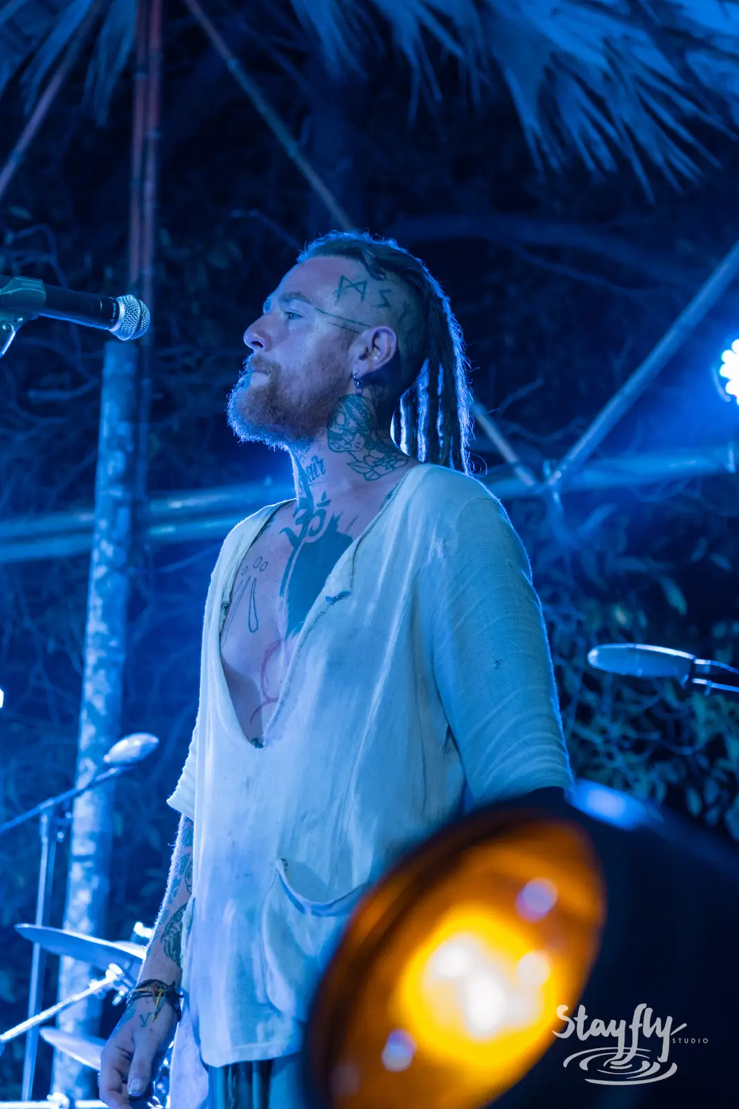 Tattooed singer performs under blue lighting.