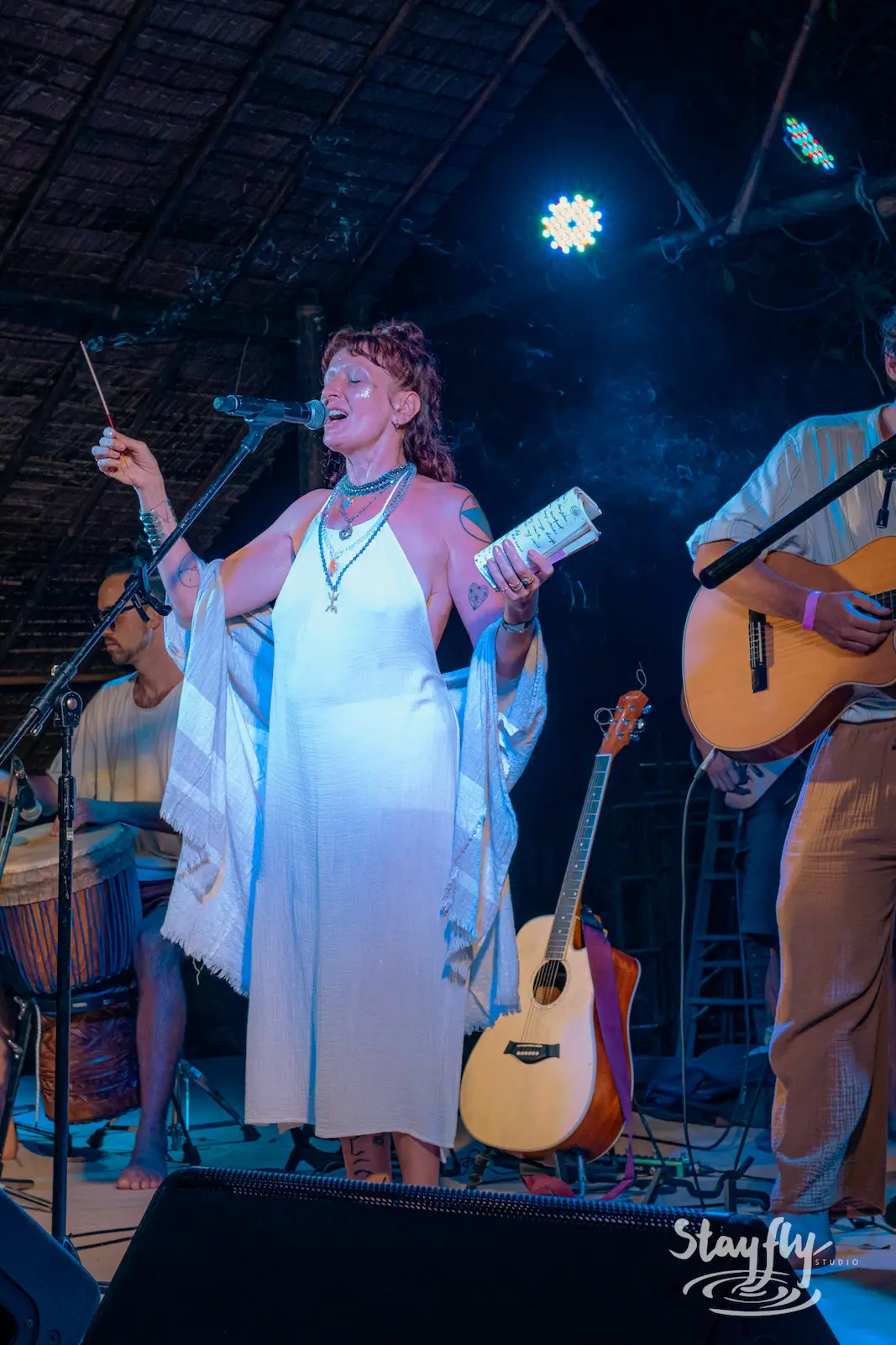 Woman sings on stage with band members.