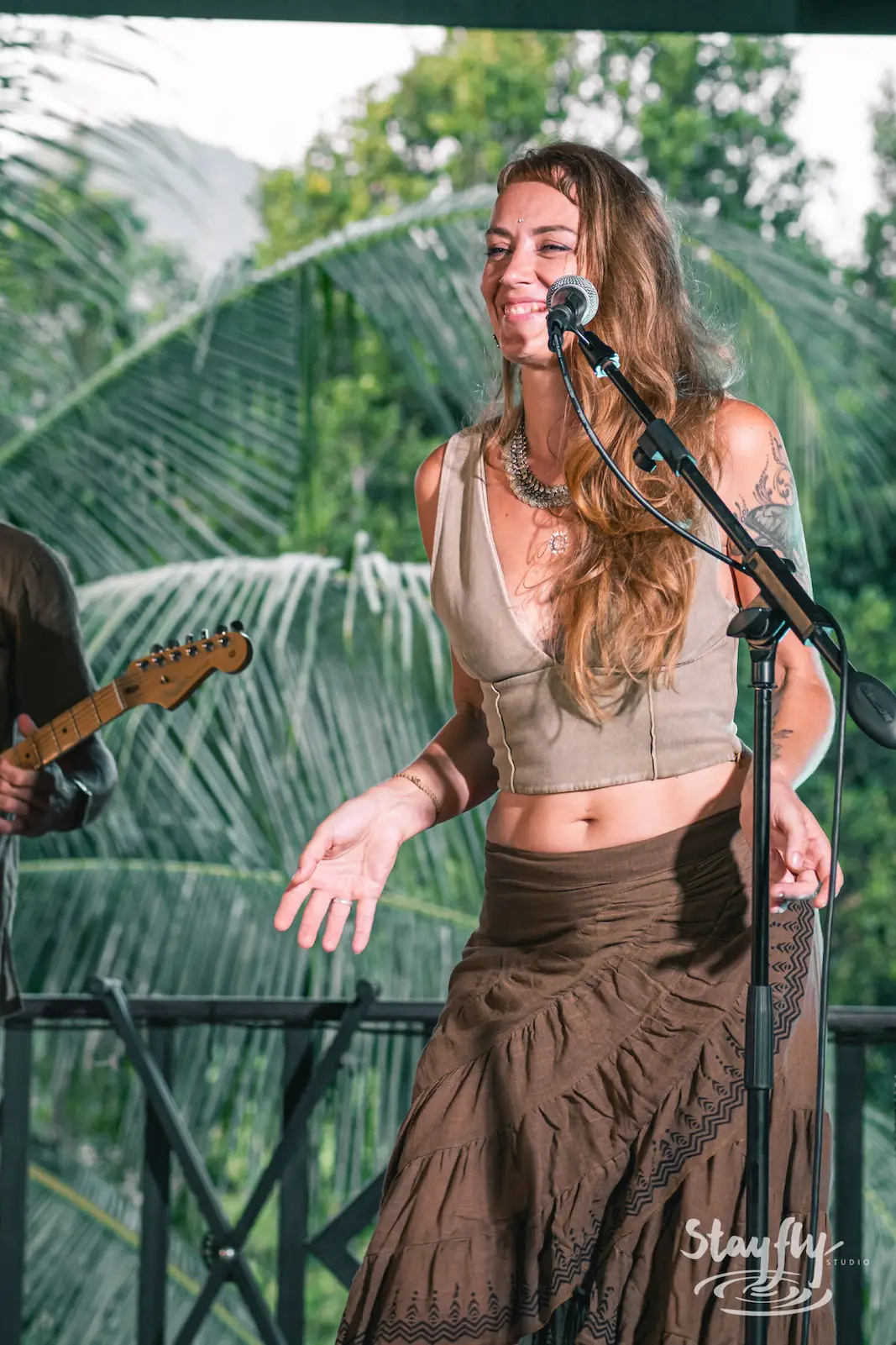 Woman singer performs against jungle backdrop.