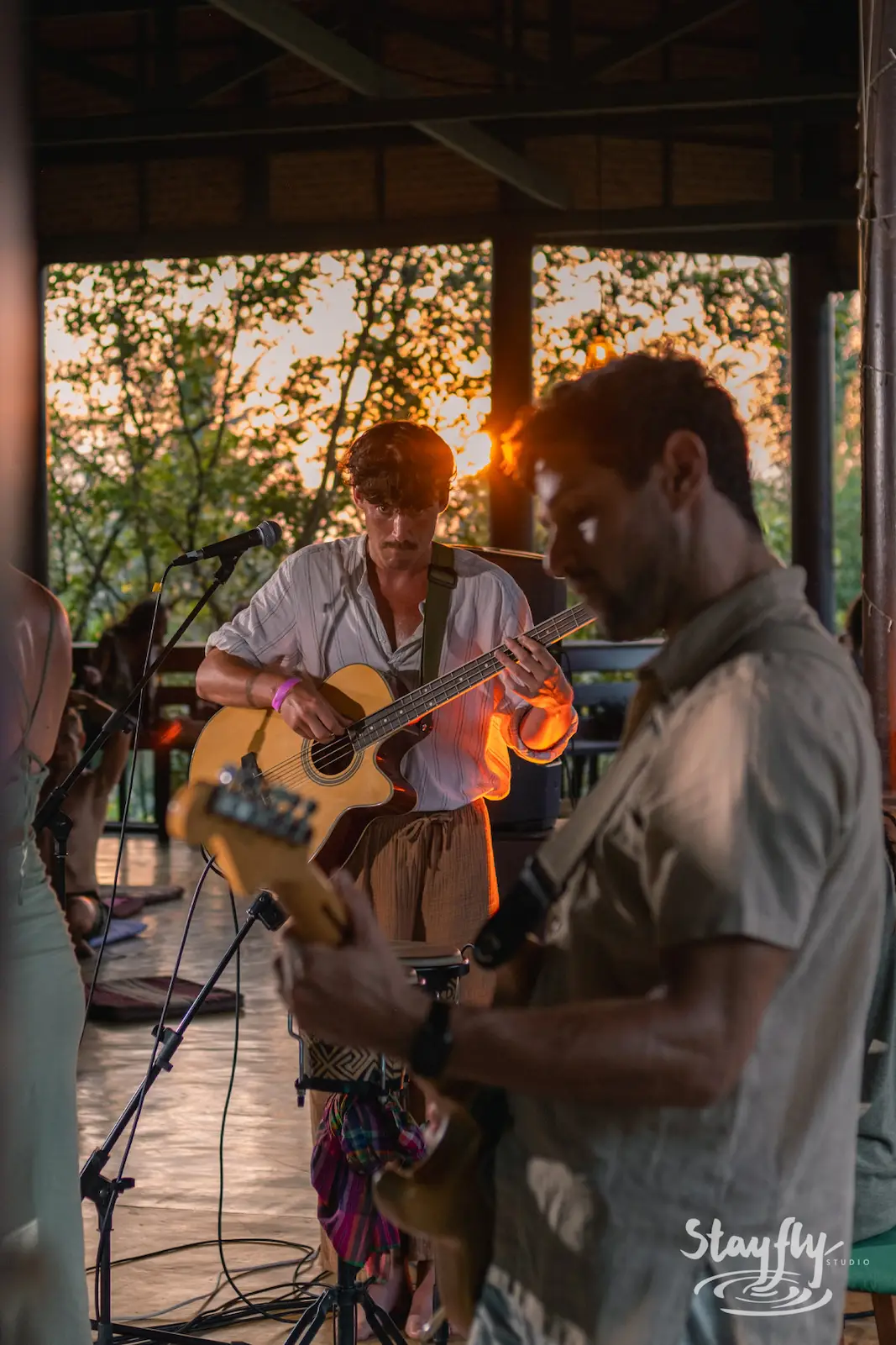 Two musicians play guitar at sunset.