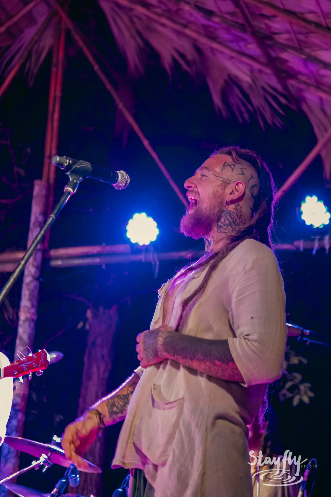 Man sings joyfully under purple stage lights.