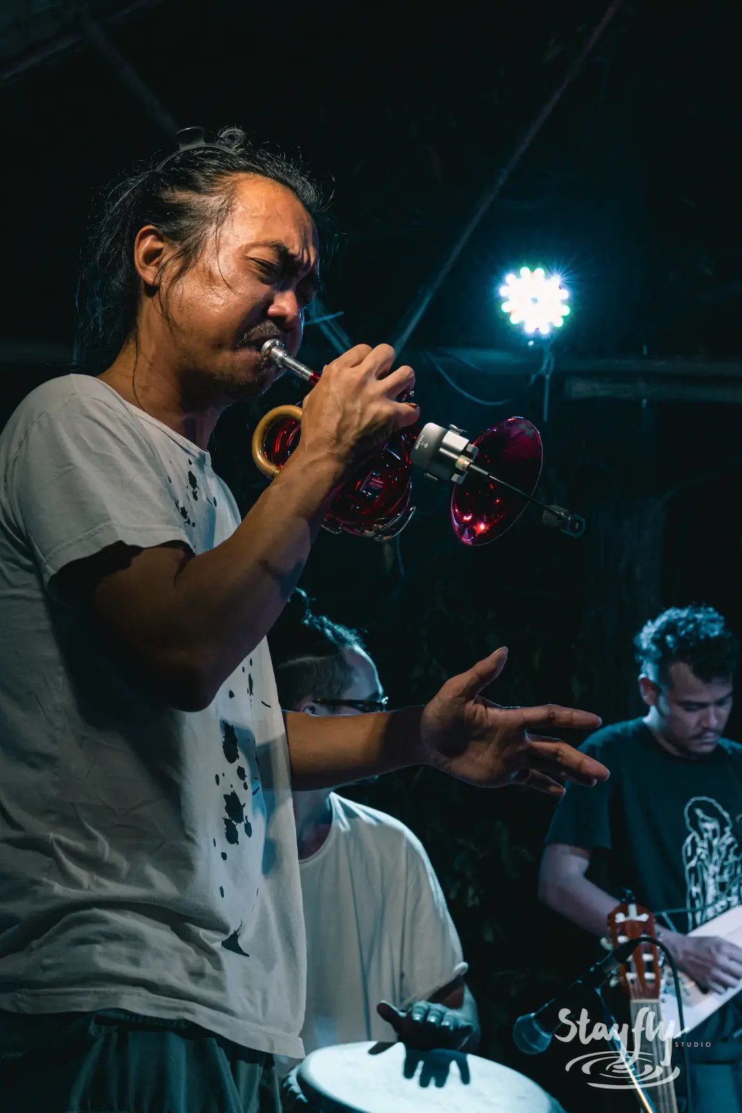 Man plays trumpet with band at night.