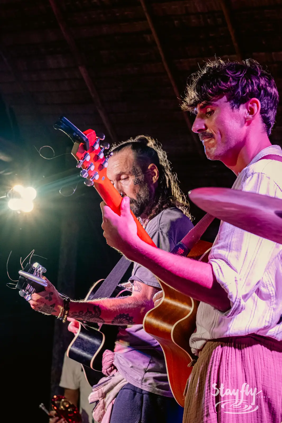 Two guitarists performing together on stage.