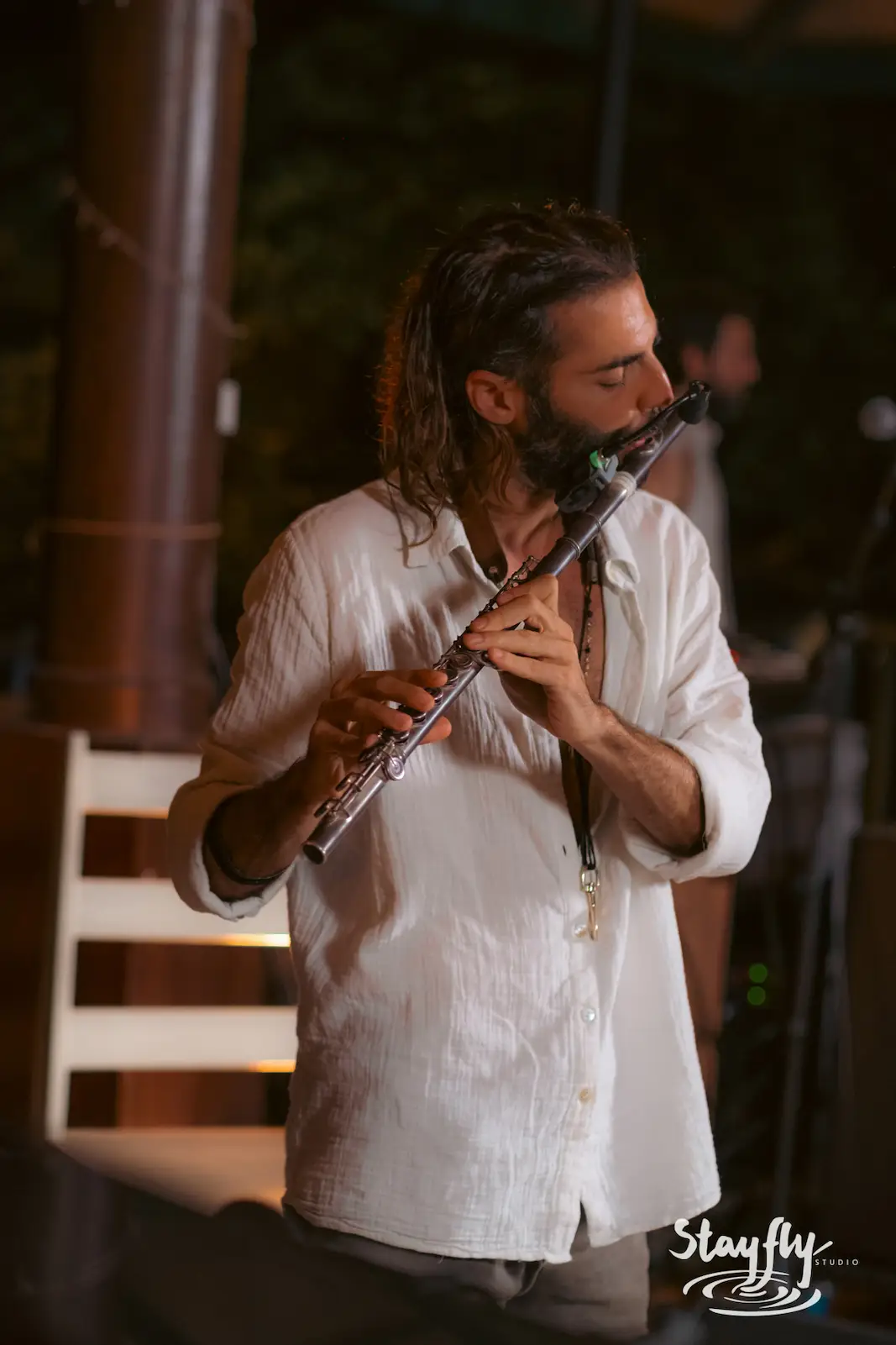 Man playing bansuri flute on stage.