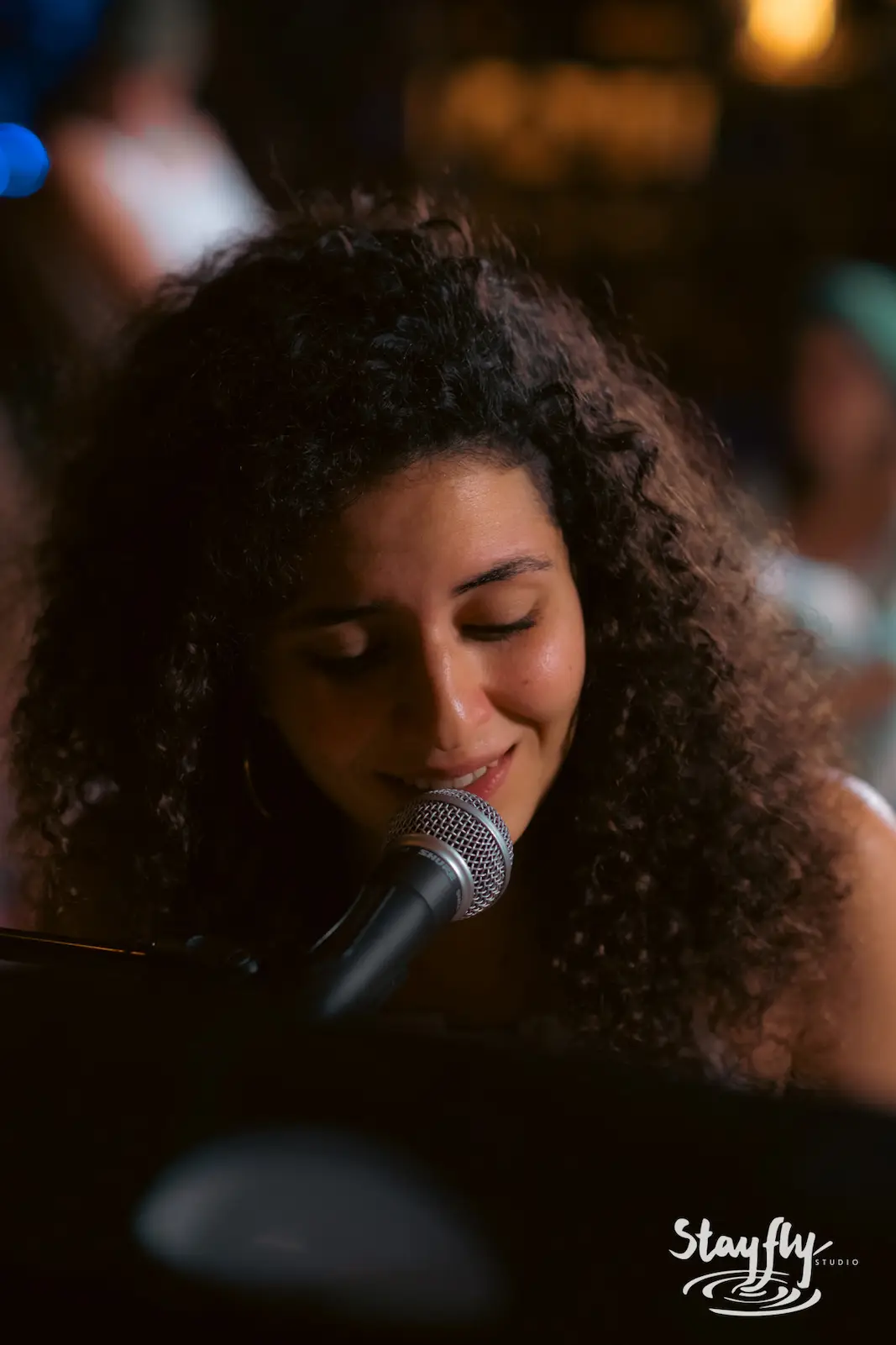 Woman singing at microphone, curly hair.