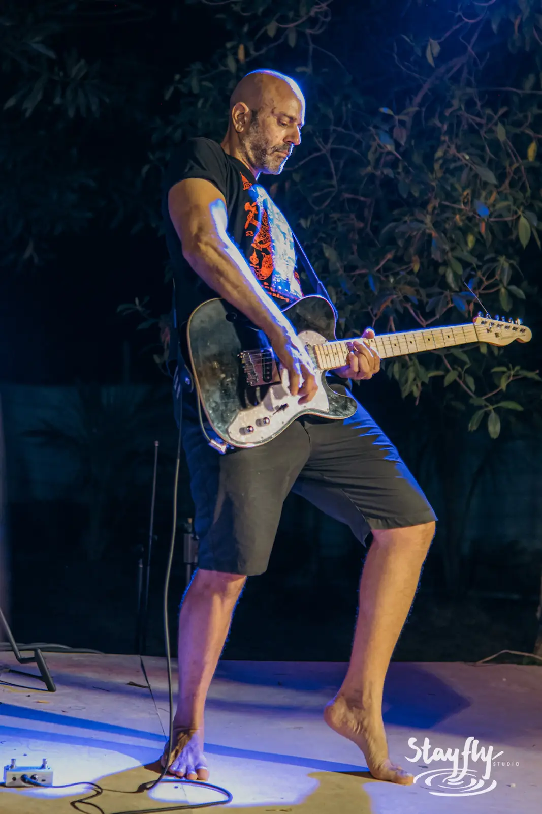 Barefoot guitarist performing on stage.