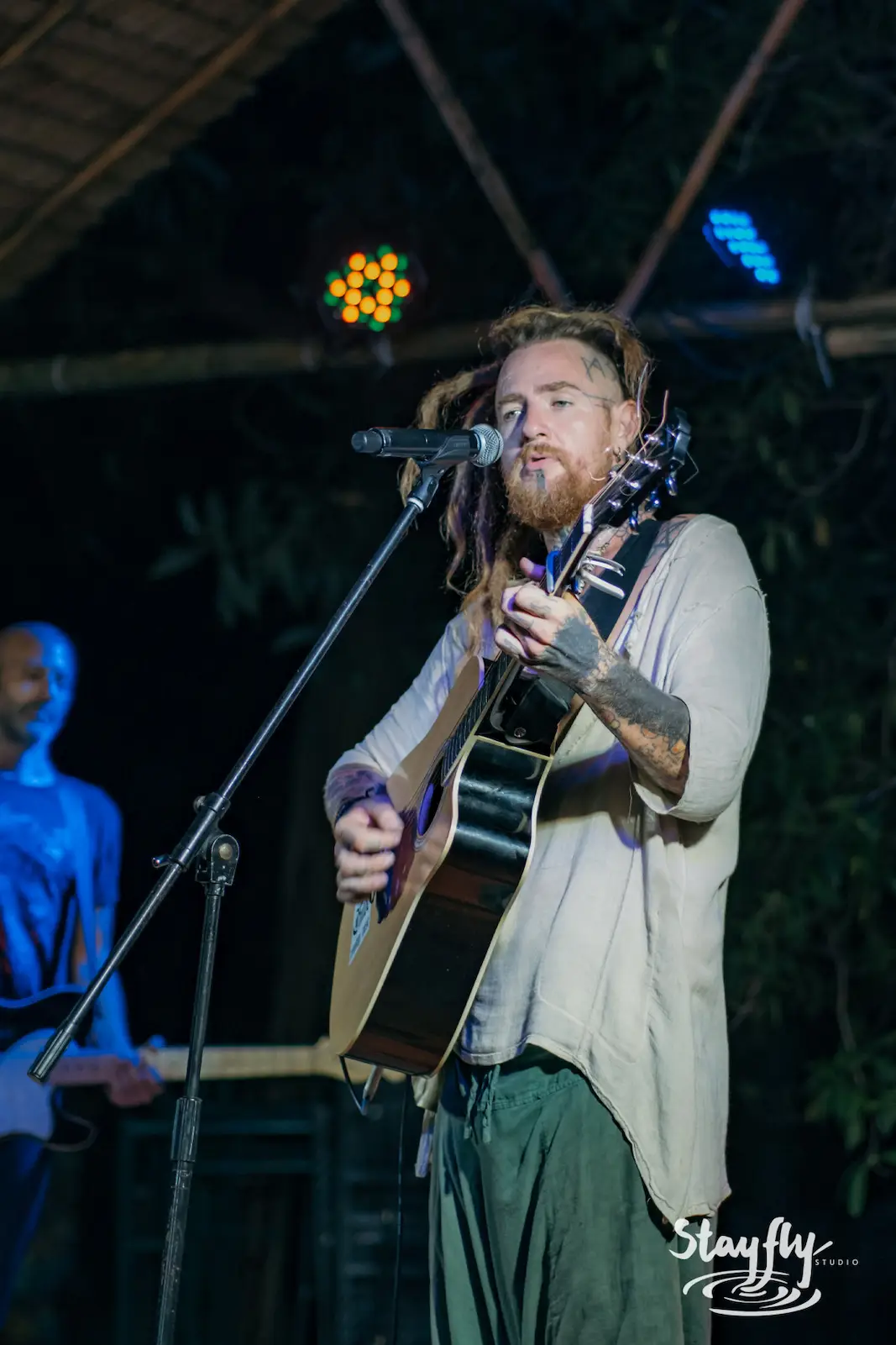 Bearded man singing and playing acoustic guitar.