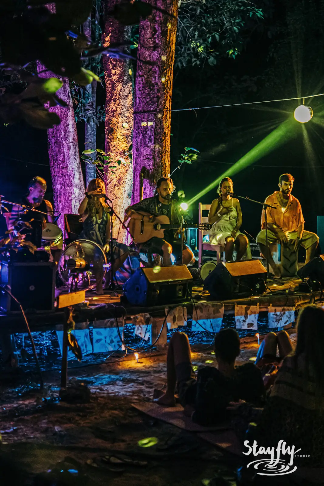 Five-piece band performing under purple stage light.
